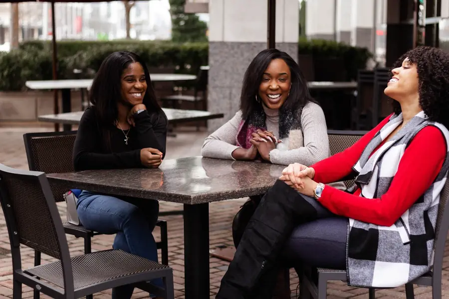 Three women laughing together around a café table